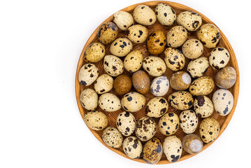 Raw quail eggs on a white background on a plate, top view, healthy eating concept