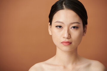 Studio portrait of serious young Vietnamese woman with natural makeup looking at camera