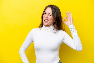 Young caucasian woman isolated on yellow background showing ok sign with fingers