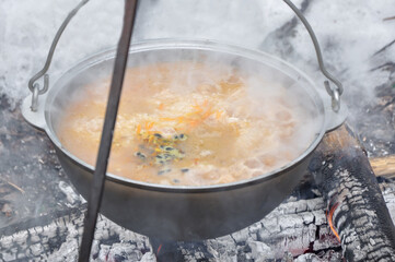 cooking pilaf in a cauldron over a fire. close-up, a large amount of steam.