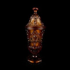 Fototapeta na wymiar crystal antique orange urn. vintage colored glass urn with engraving on a black isolated background