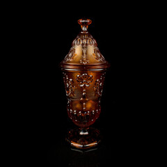crystal antique orange urn. vintage colored glass urn with engraving on a black isolated background
