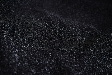 Black wrinkled fabric with sequins.Draped material. Glowing texture. Night sky