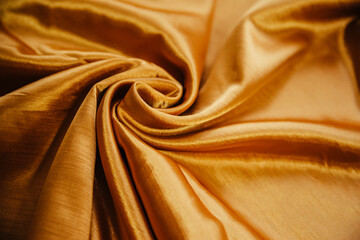 A golden wrinkled fabric lies in folds on a draped table.