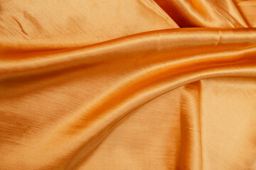 A golden wrinkled fabric lies in folds on a draped table.
