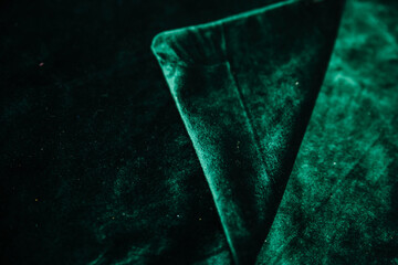 A green, wrinkled fabric lies in folds on a draped table. Emerald velvet.