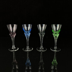 a set of antique colored wine glasses on curly legs. set of glass vintage wine glasses on a black isolated background