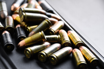 Pile of 9mm pistol bullets on taplet keyboard and screen, soft and selective focus, concept for...