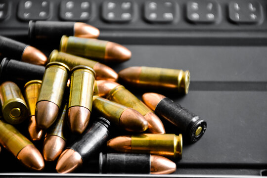 Pile of 9mm pistol bullets on taplet keyboard and screen, soft and selective focus, concept for learning types of bullets by using smart devices to search and store the database.
