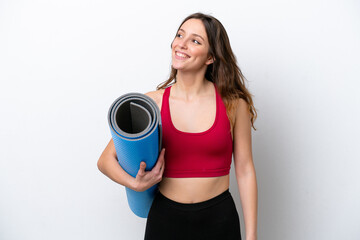 Young sport caucasian woman going to yoga classes while holding a mat isolated on white background thinking an idea while looking up
