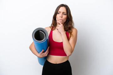 Young sport caucasian woman going to yoga classes while holding a mat isolated on white background having doubts and thinking