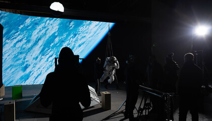 Behind the scenes of virtual production shot - Film crew working with Caucasian female astronaut...