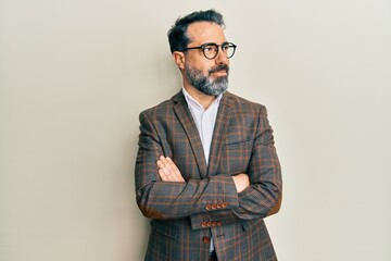 Middle age man with beard and grey hair wearing business jacket and glasses smiling looking to the...