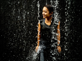 Young asian woman have fun with small waterfall	
