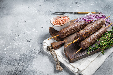 Grilled kofta kofte shish kebab from mince lamb and beef meat on Skewer. Gray background. Top view....