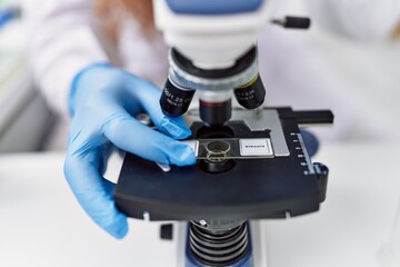 Fototapeta na wymiar Young redhead man wearing scientist uniform using microscope at laboratory