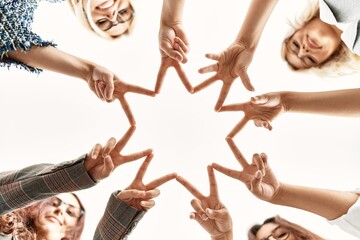Group of young businesswoman smiling happy making victory symbol with hands and fingers together at the office.