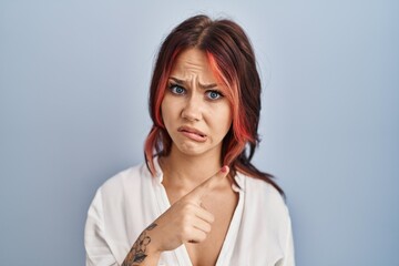 Young caucasian woman wearing casual white shirt over isolated background pointing aside worried and nervous with forefinger, concerned and surprised expression