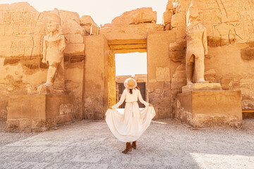 Happy woman traveler explores the ruins of the ancient Karnak town in the heritage city of Luxor or...