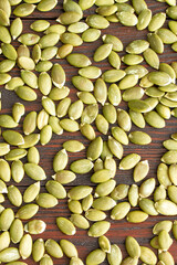 Pumpkin seeds on a wooden background. Healthy food. Scattered seeds of pumpkin. Flat lay.Vertical orientation
