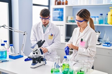 Young man and woman scientists workers wearing gloves at laboratory