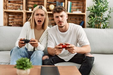 Young caucasian couple concentrated playing video game at home.