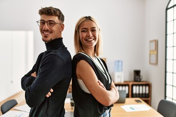 Two business workers smiling happy with arms crossed gesture standing at the office.