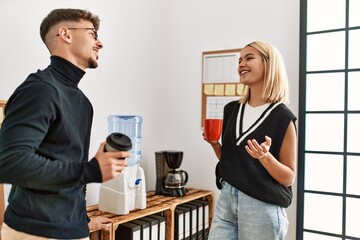 Two business workers smiling happy drinking coffee at the office.