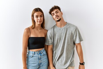 Young beautiful couple standing together over isolated background looking sleepy and tired, exhausted for fatigue and hangover, lazy eyes in the morning.