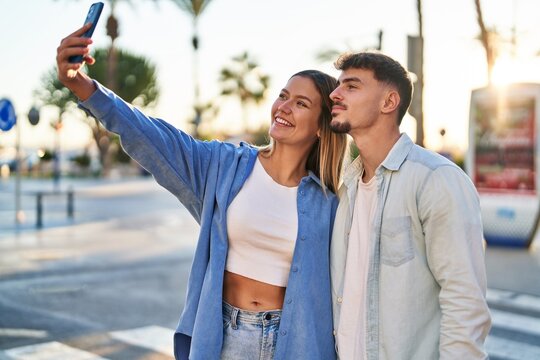 Young man and woman couple smiling confident making selfie by the smartphone at street