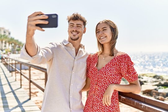 Young hispanic couple on vacation smiling happy make selfie by the smartphone at the beach