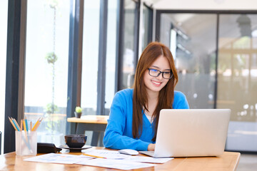 A female college student uses a computer to access the Internet for online learning