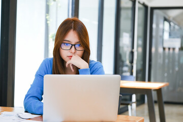 A female college student uses a computer to access the Internet for online learning.