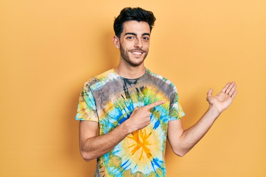 Young hispanic man wearing casual clothes amazed and smiling to the camera while presenting with hand and pointing with finger.