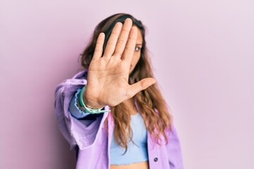 Young hispanic girl wearing casual clothes doing stop sing with palm of the hand. warning expression with negative and serious gesture on the face.