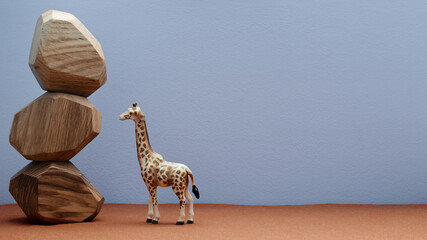 Giraffe plastic toy figure next to wooden stone blocks stacked.