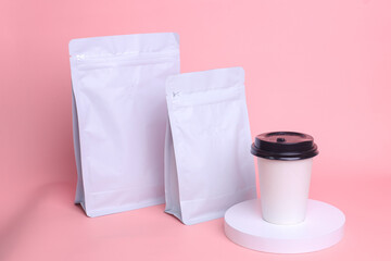 White standing pouch bags with zip lock and valve, white paper cup, on blue background, coffee set...
