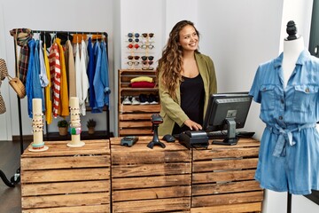 Young hispanic shopkeeper woman smiling happy working at clothing store.