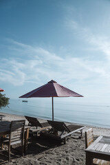 Sun umbrella and wooden beach beds on tropical coastline, Lombok, Indonesia