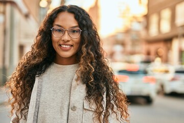 Young latin woman smiling happy standing at the city.