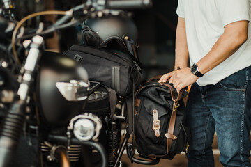 Fototapeta na wymiar rider install a motorcycle saddlebag or side bag on luggage bracket vintage motorbike. motorcycle travel concept. selective focus