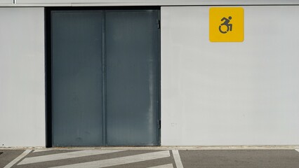 sidewalk of industrial building facade with wheelchair sign