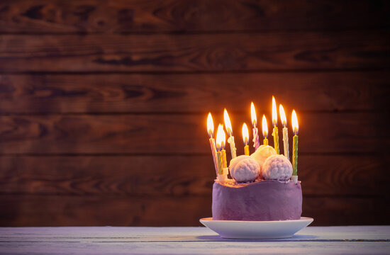 Purple Birthday Cake With Burning Candles On Dark Wooden Background