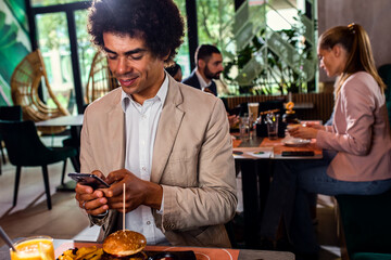 Smiling African American businessman having lunch in restaurant.