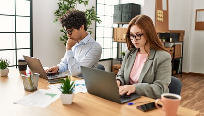 Two business workers with serious expresison working using laptop at the office.