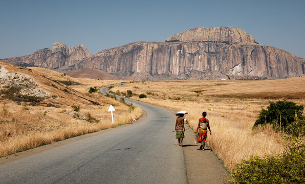 Scenic rock formation named Fandana the gateway to the south, southwest Madagascar in Africa, with two local women walking on the side of the national road 7, carrying food and baby