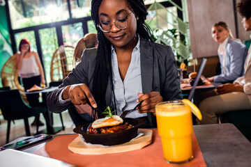 Fototapeta na wymiar Smiling African American businesswoman having lunch in restaurant.