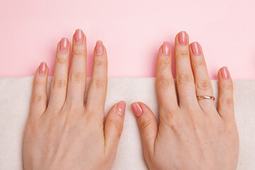 girl's nails with regrown gel coating, untidy and well-groomed hand with fresh manicure gentle nude coating.