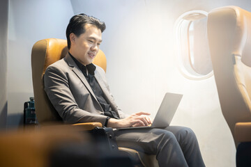 Young asian Businessman sitting in airplane cabin business class and chatting online, checking...