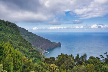 A beautiful scenic view of the coast and mountains of Madeira. Clouds, sea, flowers in spring. Madeira, Portugal.